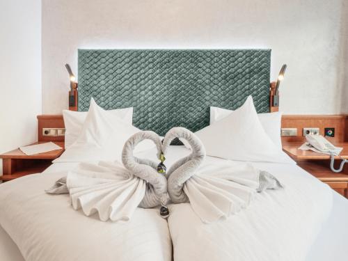 two swans forming a heart on a bed at Hotel Alpenjuwel 4 Sterne Superior in Tux