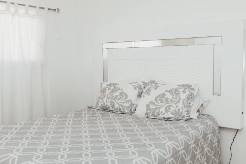 a white bedroom with a bed with pillows at Casa Puesta Del Sol An Oceanview House in El Suazal