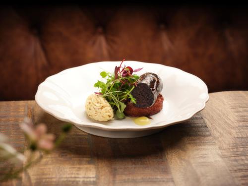 a white plate with food on a wooden table at The Bryntirion Inn in Llandderfel
