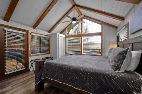 ein Schlafzimmer mit einem Bett in einem Zimmer mit Fenstern in der Unterkunft Cozy Blue Cottage with Hot Tub, 5min to Downtwn Gatlinburg in Gatlinburg