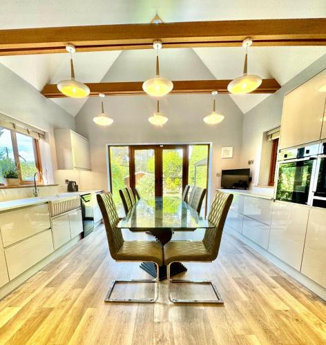 a kitchen with a glass table and chairs in it at Serene Retreat - Hot Tub - Pool Table - Close to New Forest and Bournemouth Beach - Sleeps 12 in Hurn