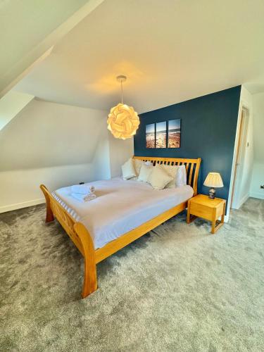 a bedroom with a large bed and a chandelier at Serene Retreat - Hot Tub - Pool Table - Close to New Forest and Bournemouth Beach - Sleeps 12 in Hurn