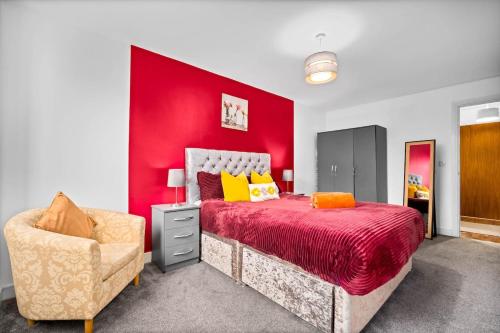 Un dormitorio con una pared roja, una cama y una silla. en Peaceful cosy stay with FREE parking, en Brierley Hill