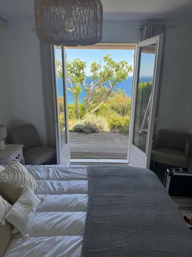 une chambre avec un lit et une porte coulissante en verre dans l'établissement Maison vue mer Palombaggia, à Porto-Vecchio