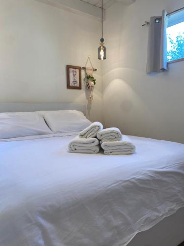 a white bed with three towels on top of it at Matar baYaar מטר ביער in El-Rom