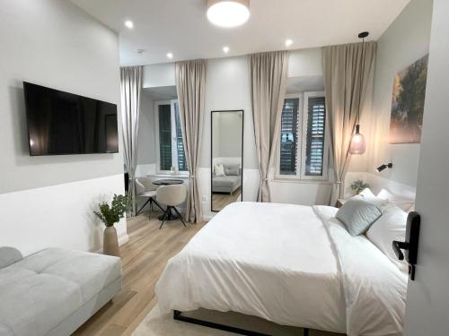 a white bedroom with a bed and a living room at Olive Rooms in Zadar