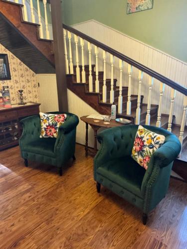 two chairs and a table in a living room with stairs at Ozark Country Inn in Mountain View