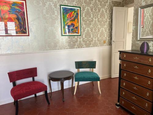 a room with two chairs and a table and a dresser at L Oranger in Rivesaltes