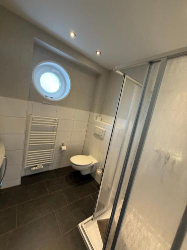 Un baño con inodoro y ventana. en Ferienwohnung Holzteichstraße 11, en Greifswald