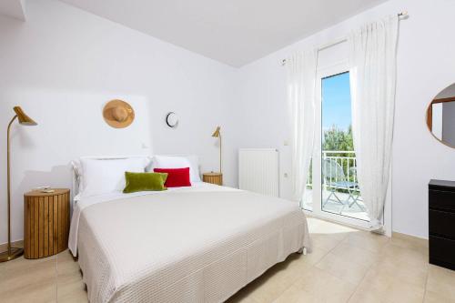 a white bedroom with a large bed and a balcony at Agapi Deluxe Villa in Skala Rachoniou