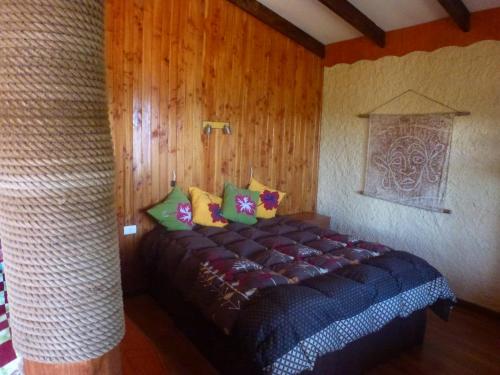 Cama en habitación con paredes de madera en Cabaña Oreko, en Hanga Roa