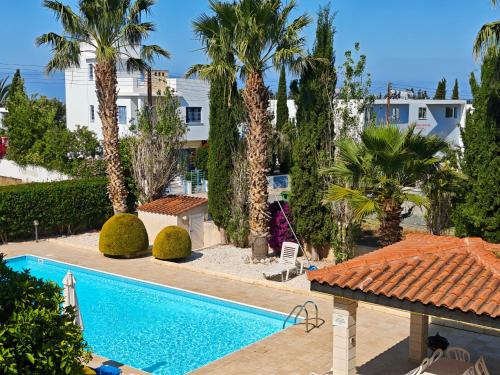a swimming pool with palm trees and a building at Sunset Green 01 in Paphos City