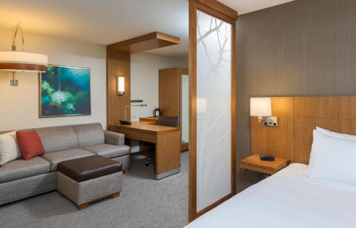 a hotel room with a bed and a couch and a desk at Hyatt Place Canton in Lake Cable