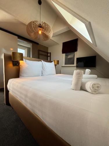 a bedroom with a large bed with white pillows at Hotel West Inn Aan Zee in Den Oever