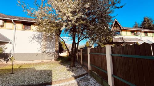 a fence with a tree in front of a house at Strigonia Apartman in Esztergom