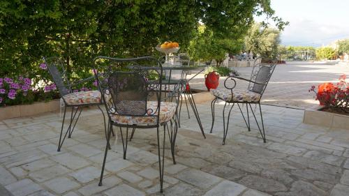 four chairs and a table with a bowl of fruit on it at Stonehouse Olivelia - Afrathias Beach in Tympáki
