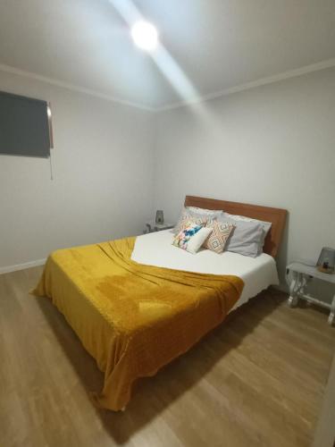 a bedroom with a bed with a yellow blanket on it at Quinta da Carlota in Povoação