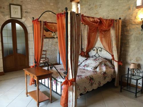 a bedroom with a canopy bed and a wooden table at Villa Charentaise avec piscine privée in Chazelles