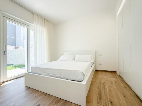 a white bedroom with a bed and a large window at TWINSANDBI Apartments A in Taranto