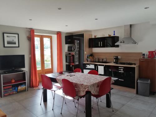 une cuisine avec une table et des chaises rouges dans une pièce dans l'établissement Etang et moulin, à La Celle-sous-Gouzon