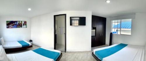 a bedroom with two beds and a tv in it at Hotel Villa Mónaco in Pereira