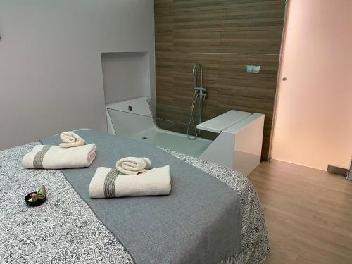 a bathroom with a bed and a shower with towels at Jerez Deluxe in Jerez de la Frontera