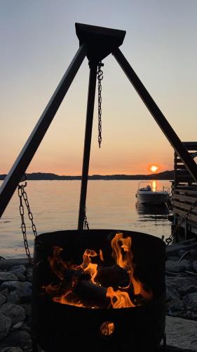 a fire pit on a boat with the sunset in the background at En Perle ved Masfjorden in Masfjorden