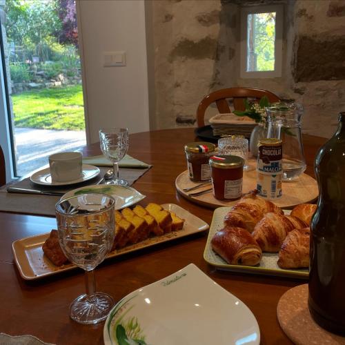 une table en bois avec des assiettes de pâtisseries et des verres à vin dans l'établissement Odonatura, à Saint-Nicolas-des-Bois