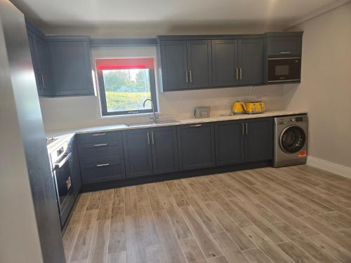 a kitchen with blue cabinets and a washing machine at Blue house, Carraroe in Carraroe
