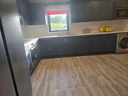 a kitchen with blue cabinets and a wooden floor at Blue house, Carraroe in Carraroe