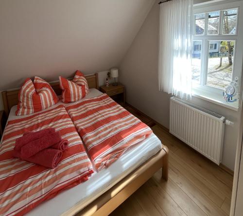 a bedroom with a bed with red pillows and a window at Ferienhaus Laran in Zingst