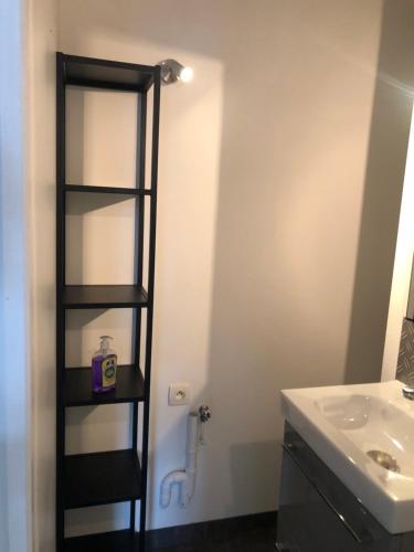 - une salle de bains avec une étagère noire à côté d'un lavabo dans l'établissement Appartement en RDC avec 1 chambre séparée, à La Celle-sous-Gouzon