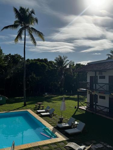 a backyard with a swimming pool and a palm tree at Pousada Casarão de Itaúnas in Itaúnas