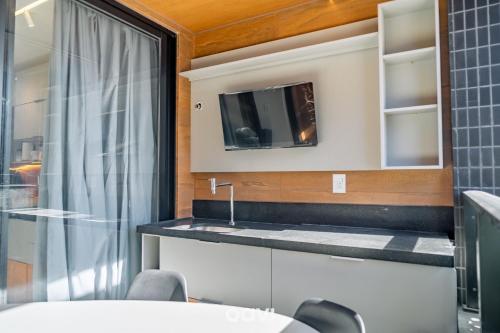Una cocina con un fregadero y un televisor en la pared. en Sun Smart por Quarto a Vista, en Ilha da Restinga