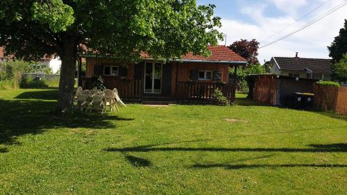 a yard with a house with chairs and a tree at Chalet du Tilleul in Poncey-lès-Athée