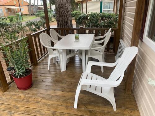 - une table et des chaises blanches sur une terrasse couverte dans l'établissement mobil home la palmeraie, à Torreilles