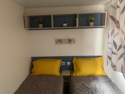 Cette petite chambre comprend 2 lits avec des oreillers jaunes. dans l'établissement mobil home la palmeraie, à Torreilles