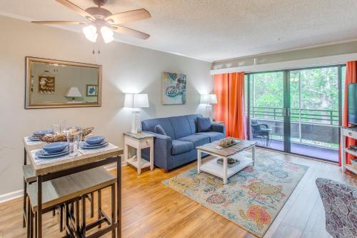 a living room with a blue couch and a table at Walk to Beach and Barefoot Landing Resort Condo! in Myrtle Beach