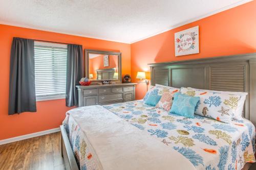 a bedroom with orange walls and a large bed at Walk to Beach and Barefoot Landing Resort Condo! in Myrtle Beach