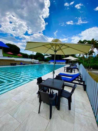 a table and chairs with an umbrella next to a swimming pool at Hotel Villa Mónaco in Pereira