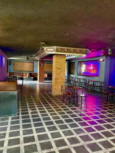 a bar with tables and chairs in a room with purple lights at Hotel Villa Mónaco in Pereira