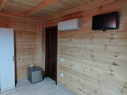 a room with a wooden wall with a flat screen tv at Bujtina Korça in Buçimas