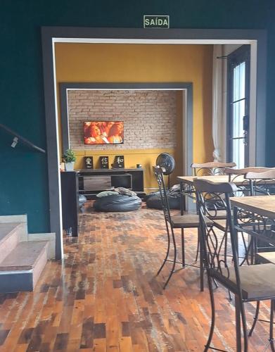a living room with tables and chairs and a fireplace at Youkoso Hostel in Florianópolis