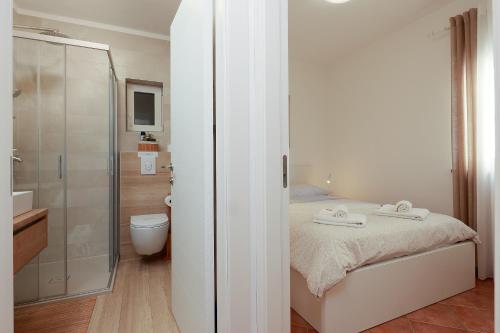 a bedroom with a shower and a bed with towels at Apartments Omanović in Čižići