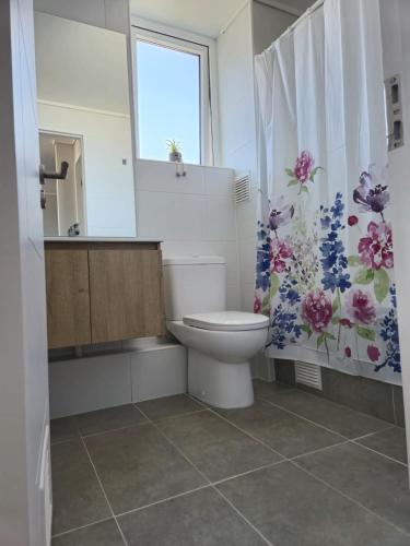 a bathroom with a toilet and a flower shower curtain at Acogedor Depto Centro de Temuco in Temuco