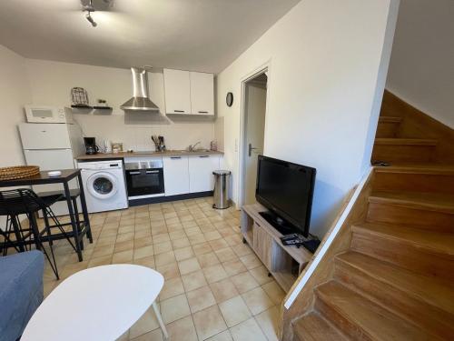 a living room with a television and a kitchen at Maison au calme , proche du parc du PDF in Pouzauges