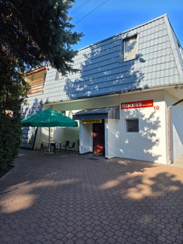 a white building with a table and an umbrella at Rooms noclegi in Bytyń