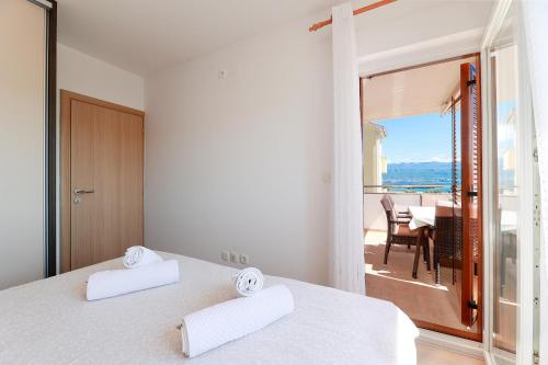 a bedroom with two white beds and a view of a table at Apartments Omanović in Čižići