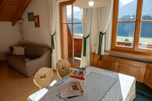 a living room with a table and a couch and windows at Im Kranzhof in San Candido