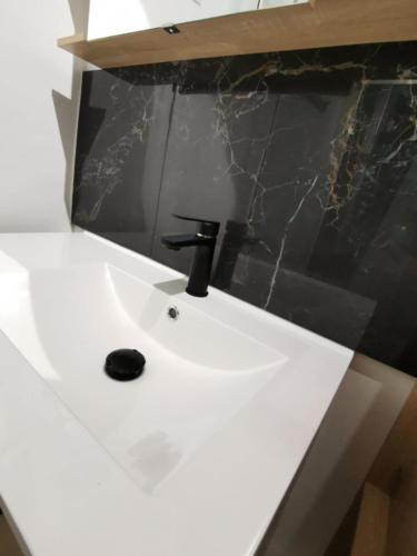 - un lavabo blanc dans la salle de bains avec un comptoir noir dans l'établissement Chez Nanou location saisonnière 2 chambres, au Tréport